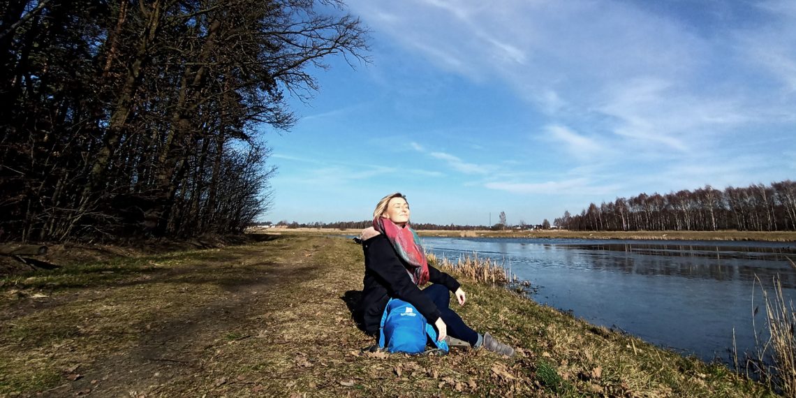 Tekst o zmaganiach Alicji Czarneckiej z depresją. Na zdjęciu: Kobieta siedząca na brzegu rzeki - HelloZdrowie