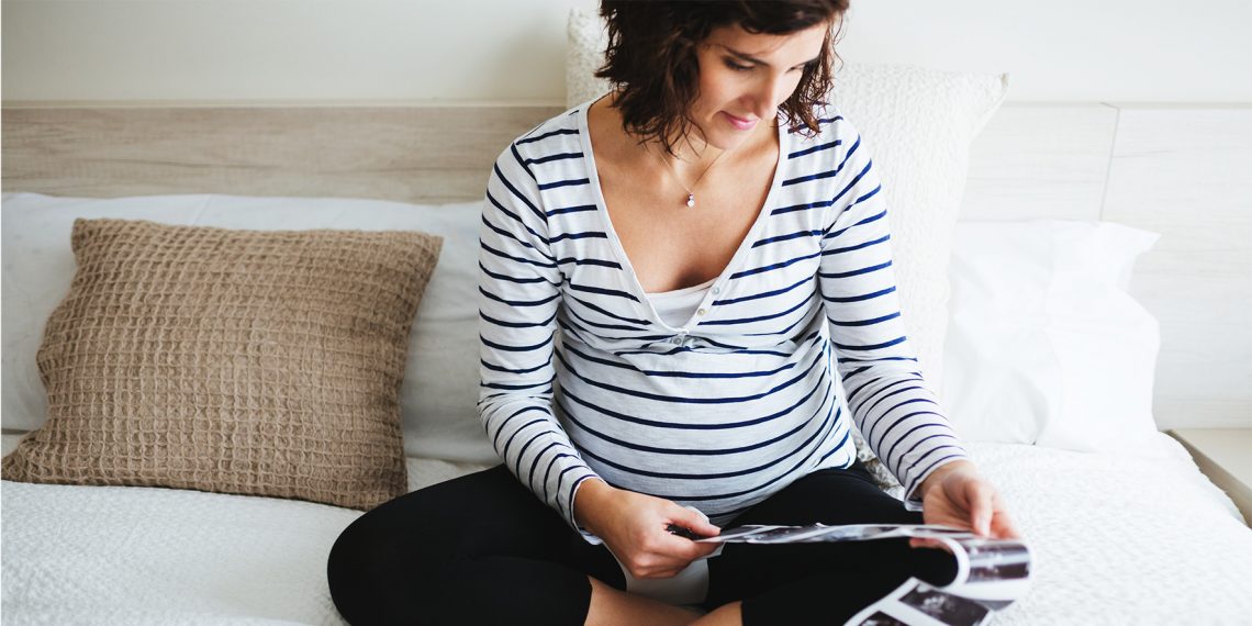 Kobieta w ciąży przegląda zdjęcia USG | Hello Zdrowie