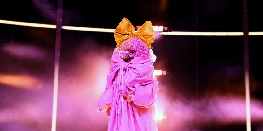 Na zdjęciu piosenkarka Sia w scenicznym image: peruka i kokarda na głowie- HelloZdrowie