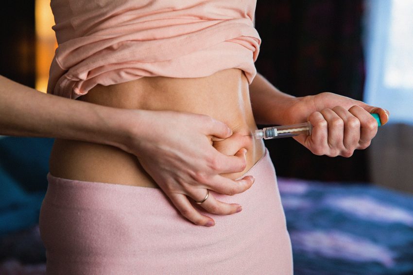 Amerykańska Agencja ds. Żywności i Leków wydała ostrzeżenie przed kupowaniem preparatów złożonych / na zdjęciu dziewczyna wbija strzykawkę z insuliną w brzuch