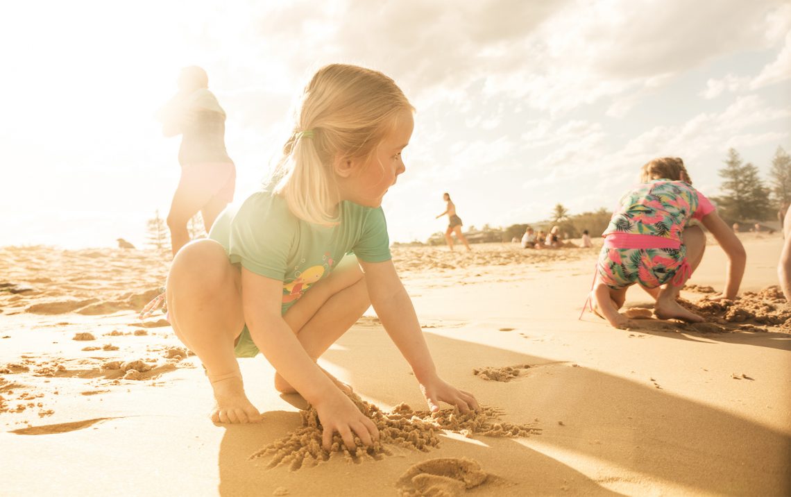 Dzieci bawią się na plaży ubrane w stroje kąpielowe