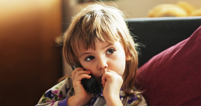 5-letnia Lena zadzwoniła na numer alarmowy 112 i uratowała życie swojej mamy - na zdjęciu dziewczynka trzyma przy uchu telefon HelloZdrowie