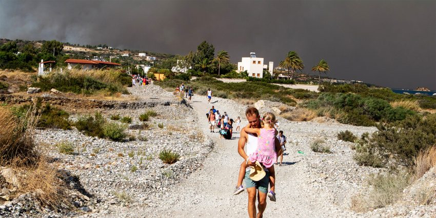 Mężczyzna wraz z dzieckiem na rękach opuszcza obszar, na którym płonie las na wyspie Rodos w Grecji, 22 lipca 2023 r. HelloZdrowie
