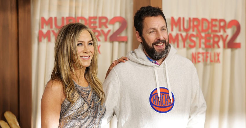 Adam Sandler wysyła kwiaty Jennifer Aniston na każdy Dzień Matki - na zdjęciu aktorzy pozują uśmiechnięci podczas premiery filmu "Zabójcze wesele" - ona w srebrnej sukience na ramiączka, on w białej sportowej bluzie z kapturem HelloZdrowie