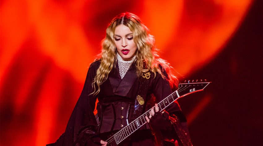Madonna z gitarą w trakcie koncertu - czerwone tło zdjęcie HelloZdrowie