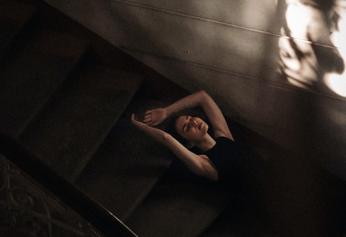 Kobieta leży na schodach, zdjęcie jest w ciemnych barwach