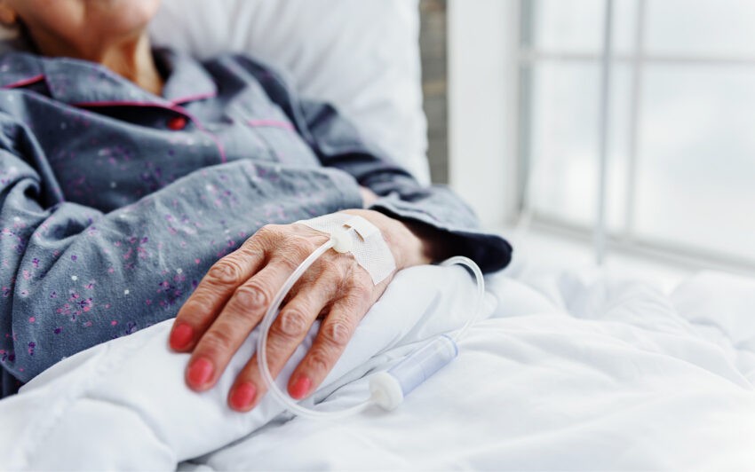 71-letnia pacjentka przez cztery dni nie jadła i nie piła czekając na operację - na zdjęciu dłoń kobiety, pomalowane na czerwono paznokcie, wenflon w dłoni HelloZdrowie