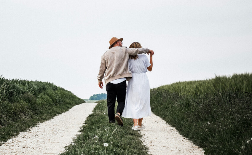 Syndrom miesiąca miodowego dotyczy nie tylko nowożeńców - na zdjęciu para podczas spaceru, ona w białej sukience, on w czarnych spodniach i beżowej bomberce HelloZdrowie