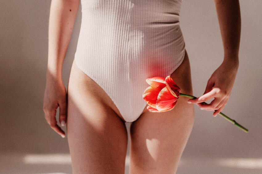 Na zdjęciu kobieta od bioder w dół w bikini, trzymająca kwiat- HelloZdrowie
