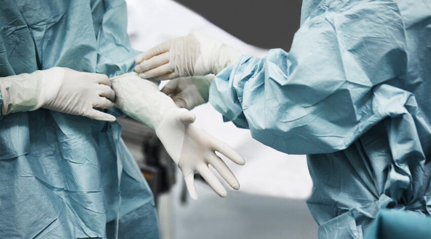 Na zdjęciu lekarze zakładający rękawiczki lateksowe przed operacją- HelloZdrowie