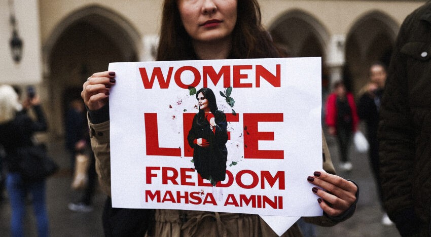 Kobieta stoi na proteście ze zdjęciem Jiny Mahsa Amini