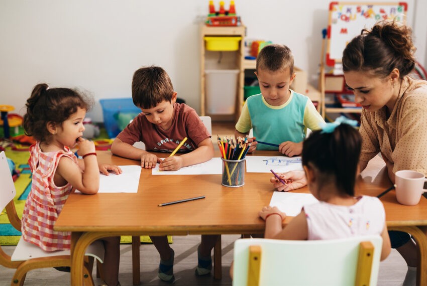 Szkarlatyna w przedszkolach - na zdjęciu dzieci siedzą przy stoliku wraz z opiekunką Hello Zdrowie