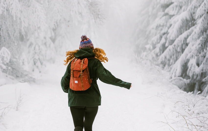 Na zdjęciu spacerująca kobieta z plecakiem w krajobrazie zimowym: Hello Zdrowie