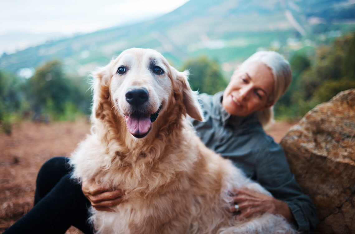 Posiadanie zwierzęcia domowego jest dobre dla mózgu - na zdjęciu dojrzała kobieta przytula psa w górach Hello Zdrowie