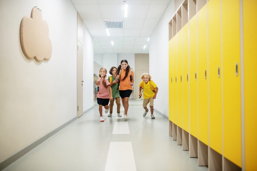 Izabela Leszczyna chce powrotu punktów szczepień w szkołach - czworo dzieci biegnie szkolnym korytarzem