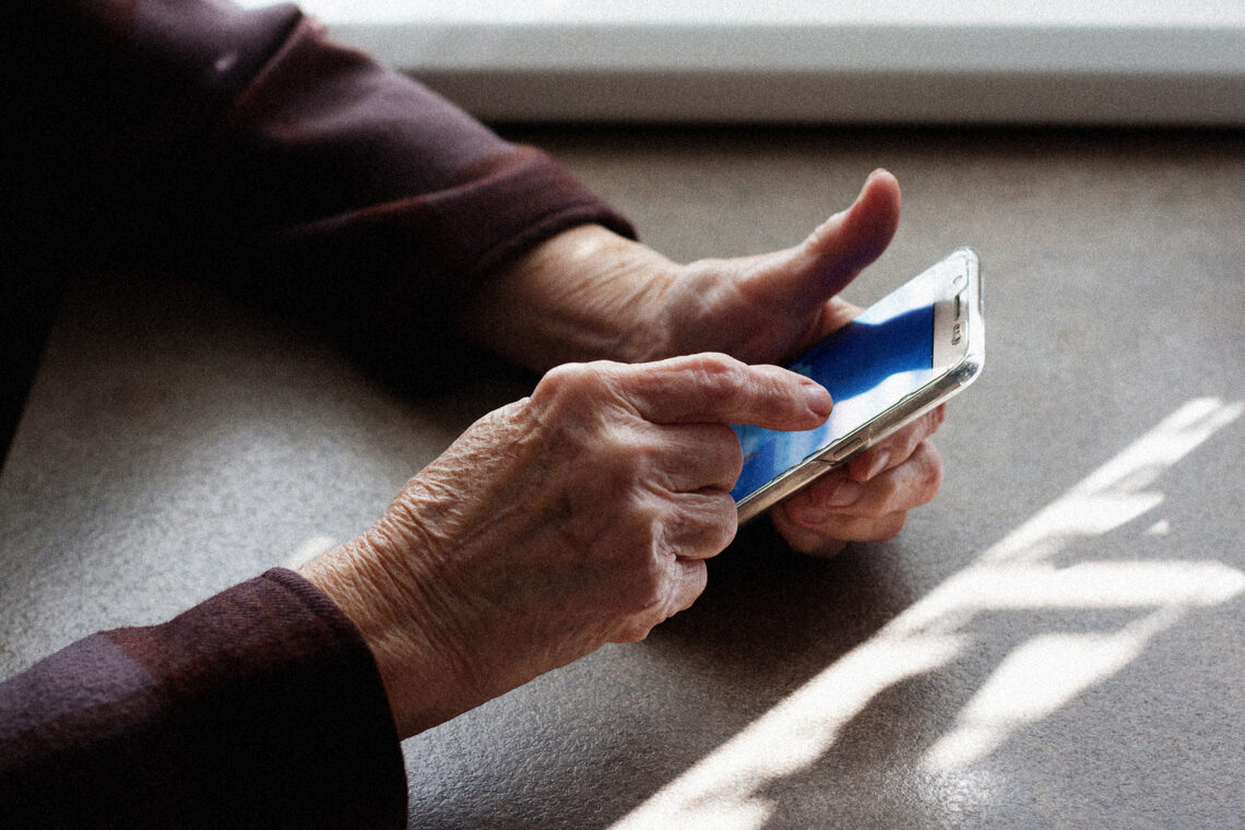 Starsza osoba dotyka ekranu smartfona