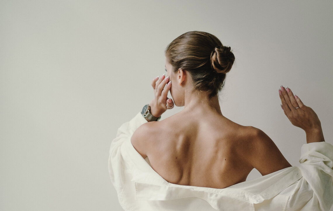 Objawy przed okresem – po czym poznać, że zbliża się miesiączka., na zdjęciu kobieta tyłem z odkrytymi plecami- Hello Zdrowie