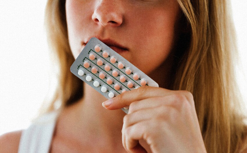 Kobieta trzyma bliester tabletek przy ustach