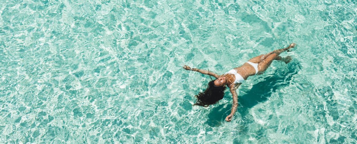 Kobieta w bikini pływa w morzu. Tekst dotyczy depilacji okolic intymnych - Hello Zdrowie