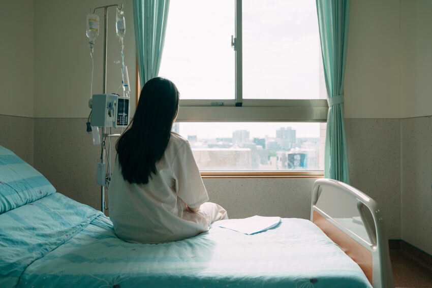 Pacjentka siedząca tyłem na łóżku - Hello Zdrowie