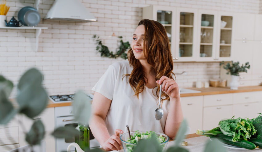 Kobieta stoi w kuchni przy stole na którym leżą warzywa na regenerację trzustki