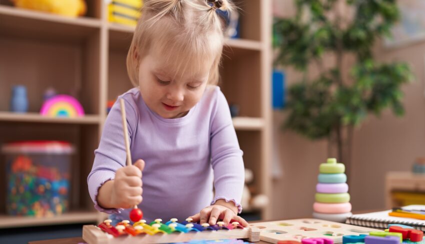 Dziewczynka w fioletowej bluzce gra na cymbałkach