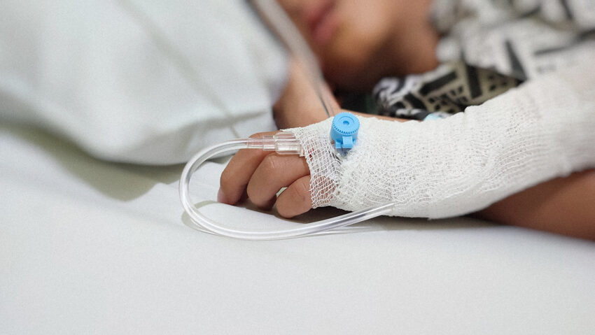 Dziecięca ręka z widocznym wenflonem i owinięta bandażem