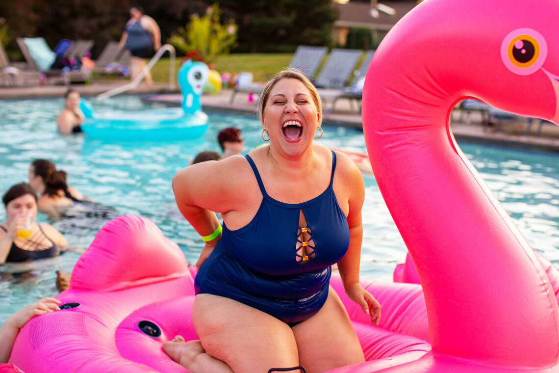 Kobieta pływa w basenie na dmuchanym różowym flamingu
