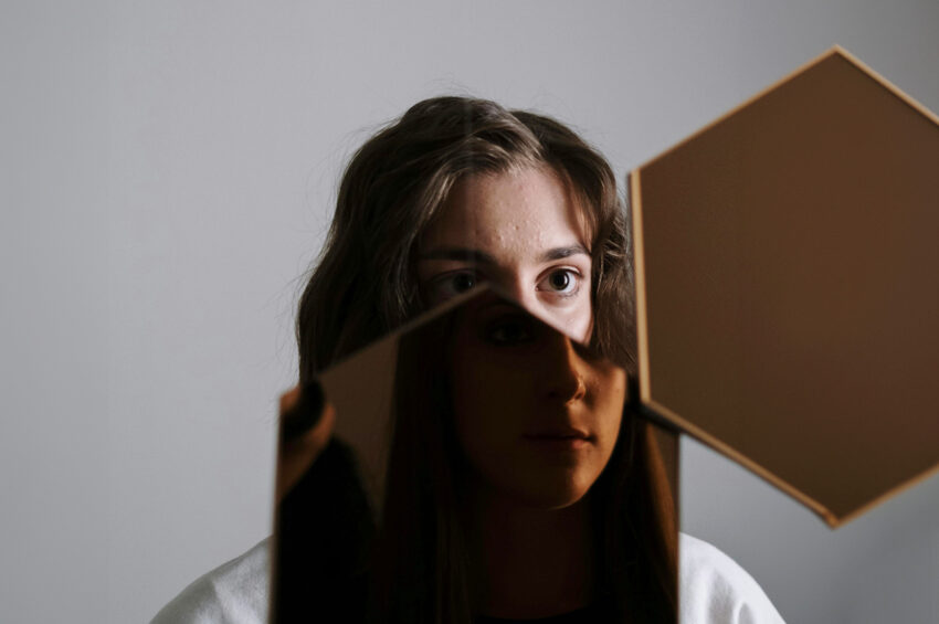 Dziewczyna przegląda się lustrze, jej twarze zdaje się skłądać z wizerunków dwóch różnych osób. tekst dotyczy profesjonalnych testów psychologicznych