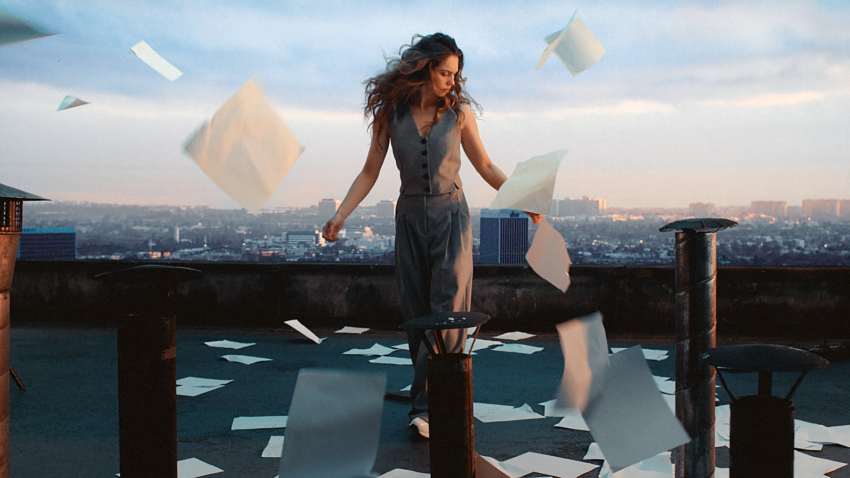 na zdjęciu: kobieta stoi na dachu budynku, wokół niej latają kartki papieru, tekst o przebodźcowaniu /fot. materiały promocyjne marki Answear