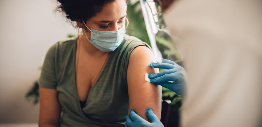 Kobieta w zielonej bluzce w trakcie szczepienia