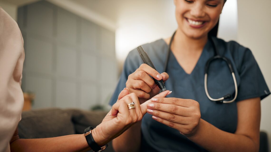 Na zdjęciu: Lekarka diabetolog wykonuje badanie glukometrem, pobierając próbkę krwi z palca pacjentki.