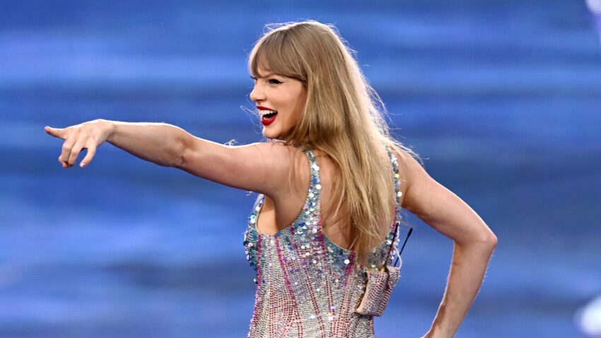 Taylor Swift uśmiecha się i wskazuje na kogoś ręką podczas koncertu w 2024, tekst o poparciu przez Swift Kamali Harris w wyborach prezydenckich