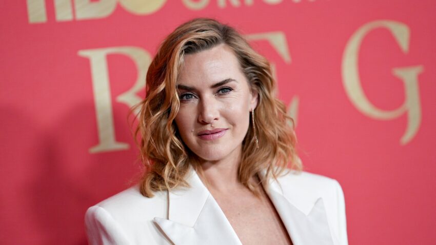 Kate Winslet w białej marynarce, w tle różowa ścianka premiera serialu "Reżim"