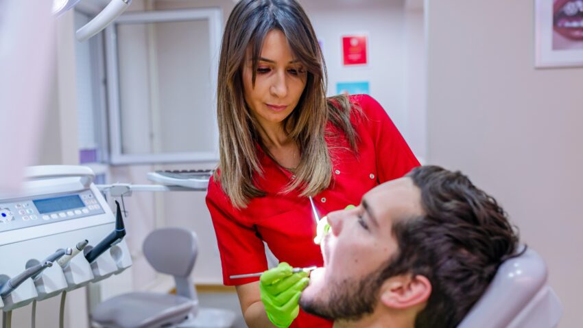 Mężczyzna na fotelu dentystycznym, dentystka bada mu zęby- Hello Zdrowie