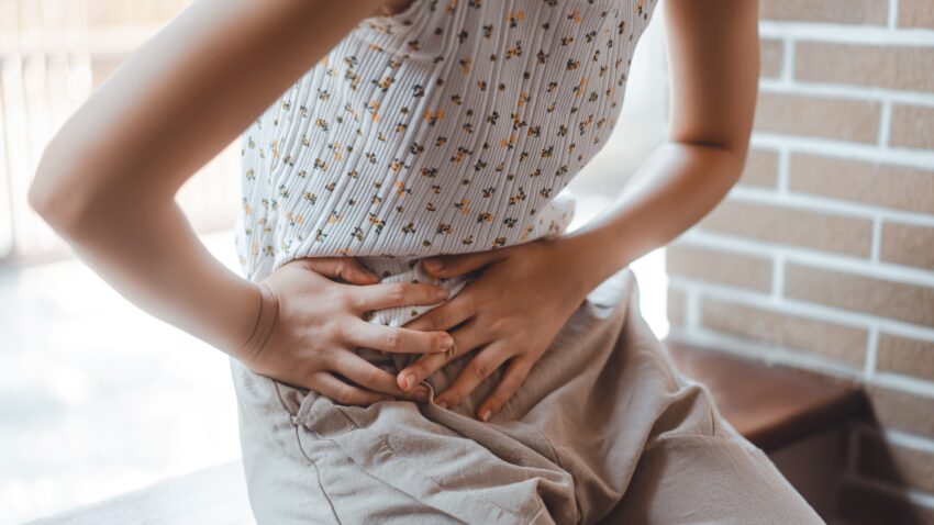 Kobieta trzyma się za brzuch. Tekst o badaniach naukowców, którzy powiązali bóle menstruacyjne z depresją