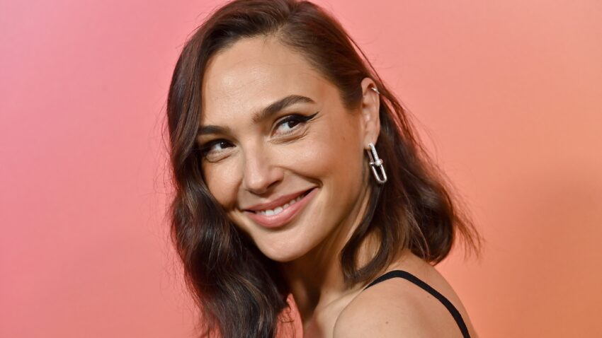 Gal Gadot uśmiecha się na tle pomarańczowej ścianki